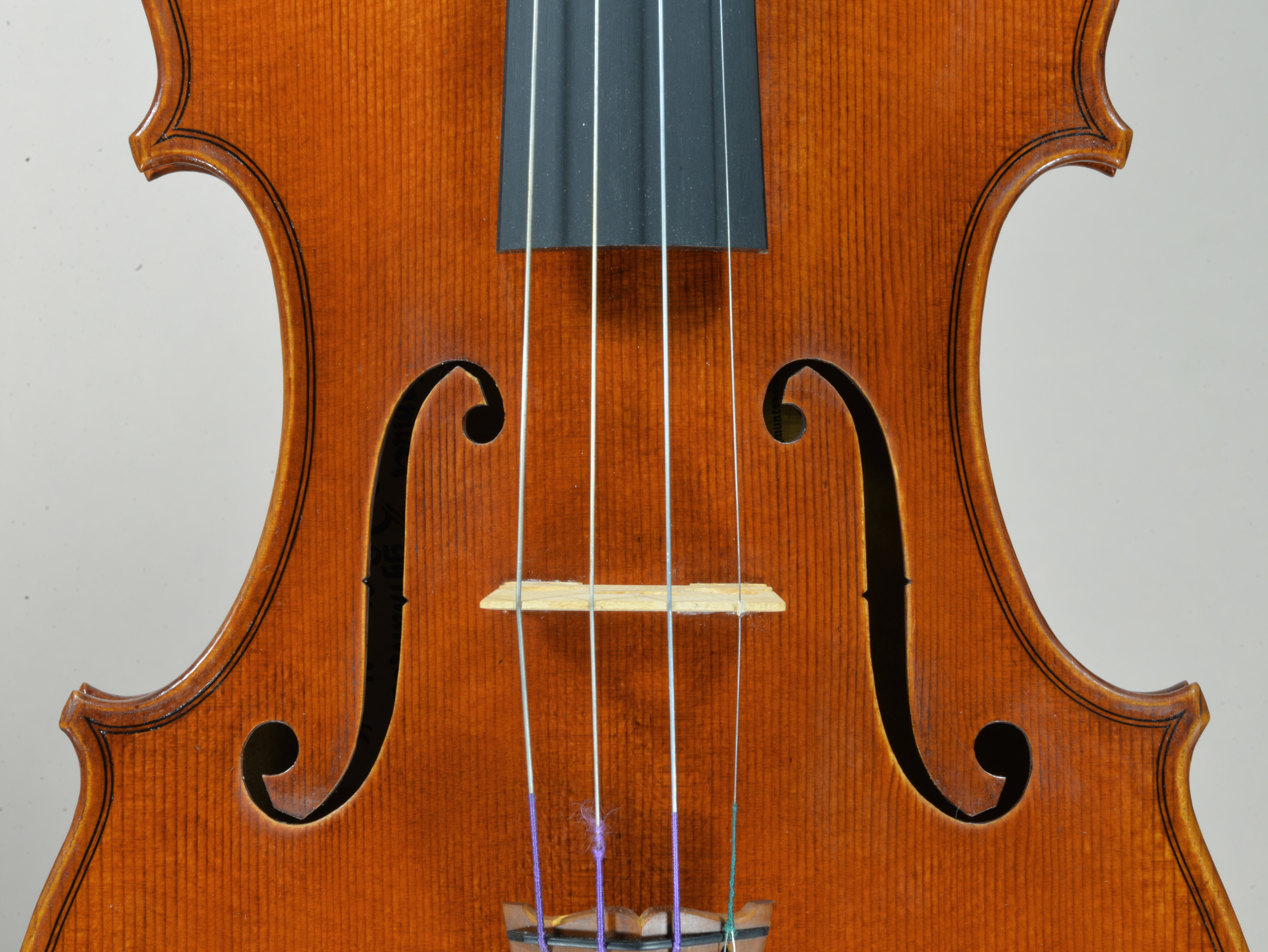 Close-up of a violin includes strings, f-holes, and rich wooden texture.