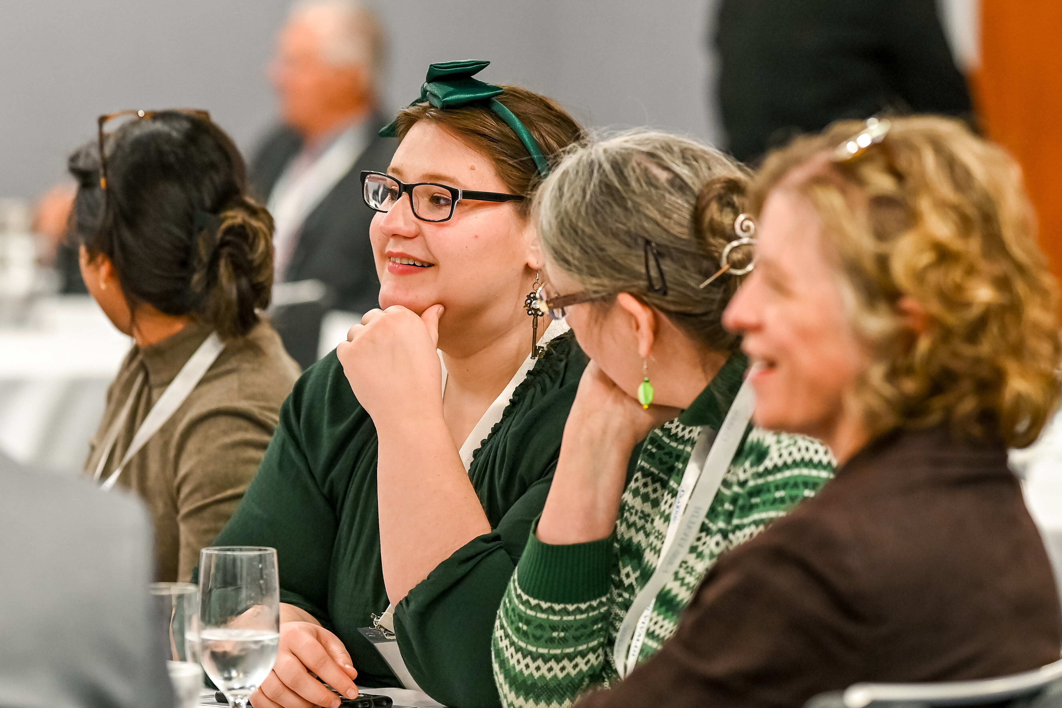 Group of women engaging in conversation at a conference table, smiling and attentive.