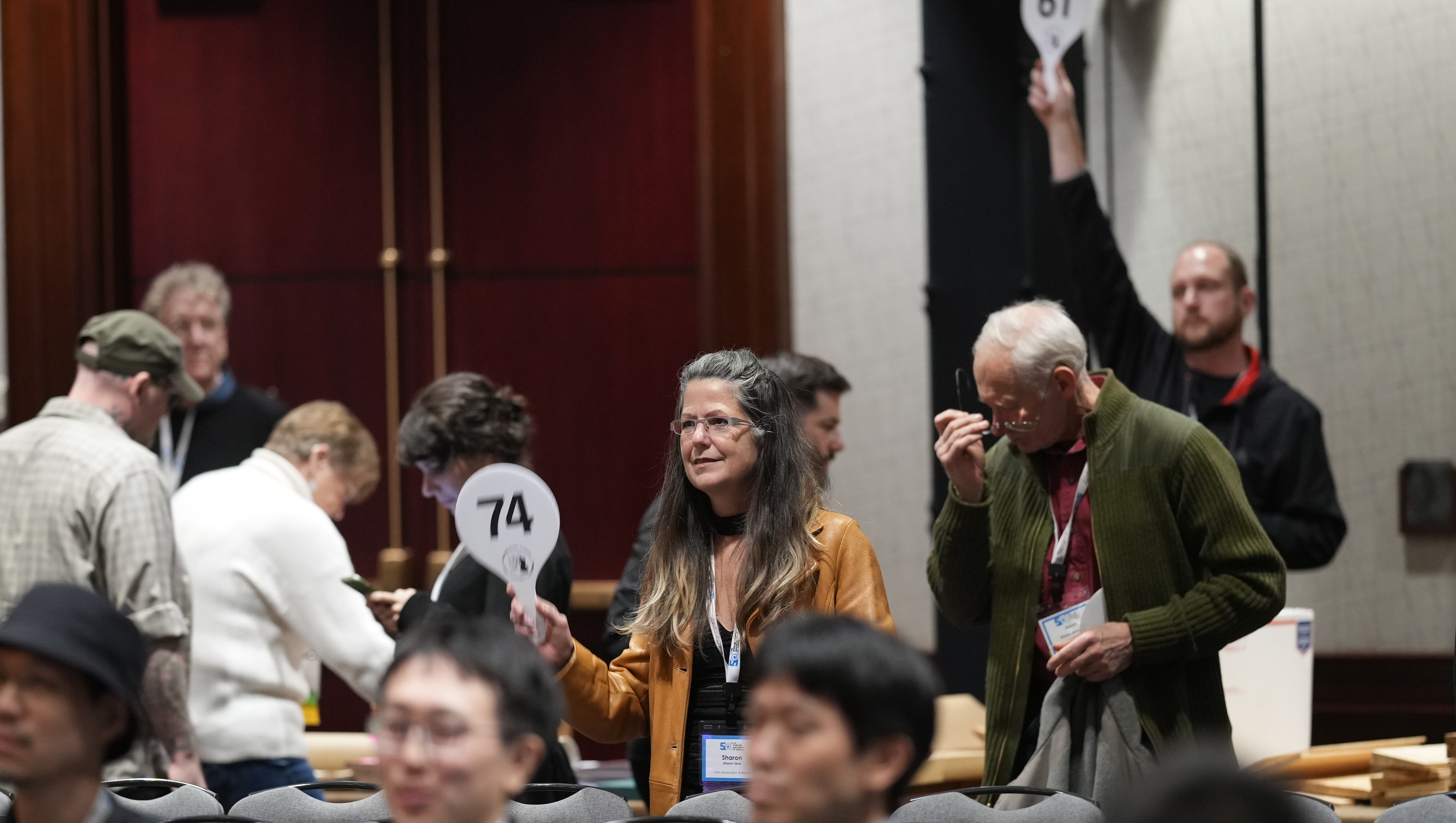 Participants in a conference holding numbered signs in a meeting setting.